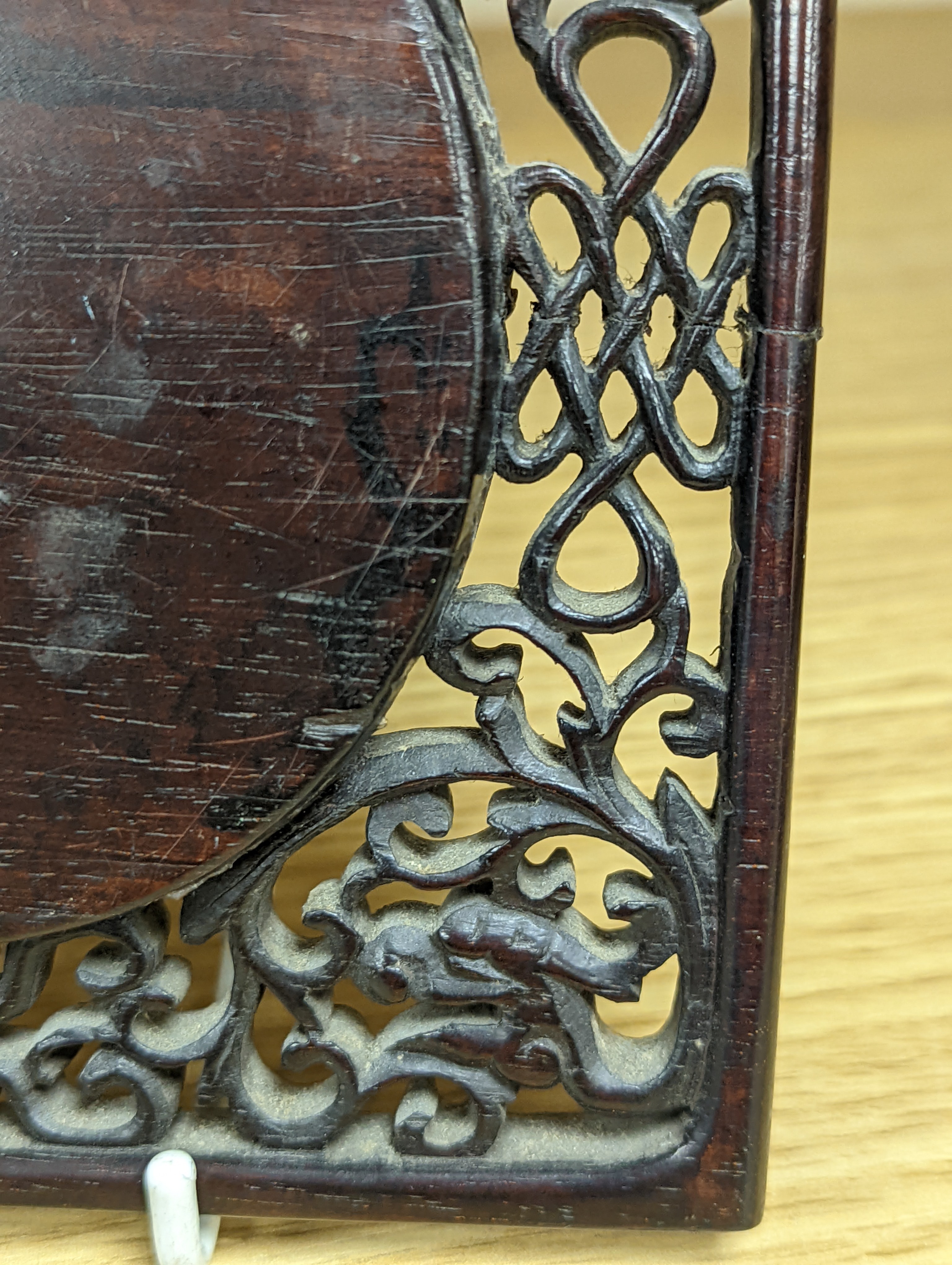 A 19th century Chinese famille rose circular plaque or cover, inset into a wood surround, cracks 15cm sq